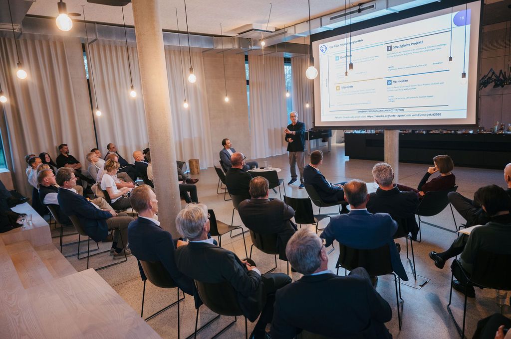 Publikum beim 1. AI Cycle bei NIMBLE in Wels, vorne die Leinwand mit den Folien des Impulses